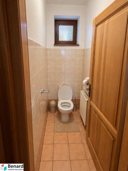 Családi ház fürdőszobájának belső tere WC-vel, ablakkal és csempével.