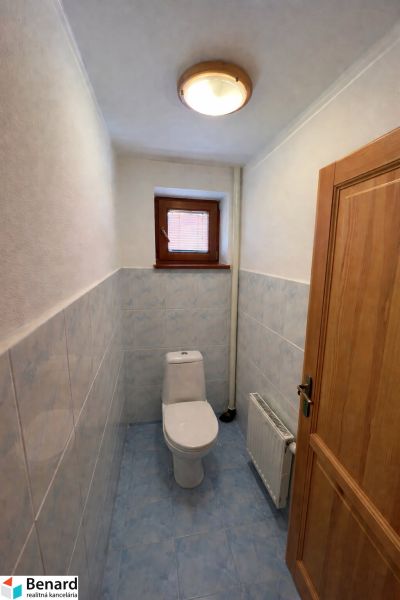 WC egy családi házban kék csempékkel és kis ablakkal.