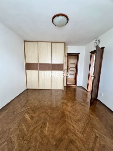 Szoba egy háromszobás lakásban fa dekoros padlóval és beépített szekrénnyel.