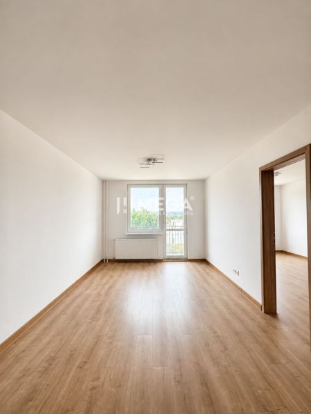 Tágas nappali szoba fa mintázatú padlóval egy háromszobás lakásban.