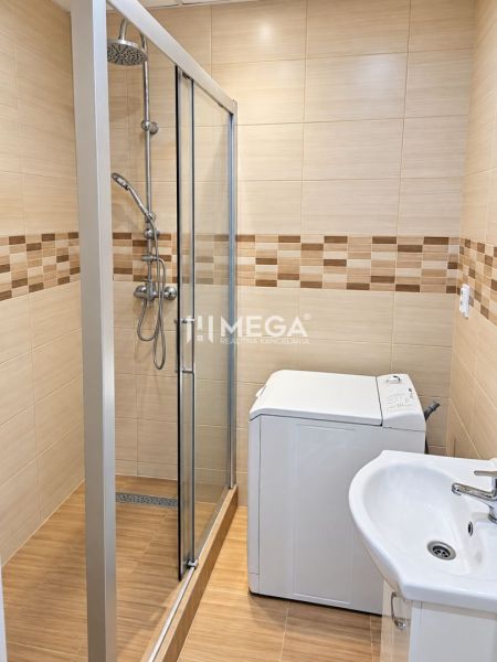 Fürdőszoba tágas zuhanyzóval és mosógéppel egy kétszobás lakásban.