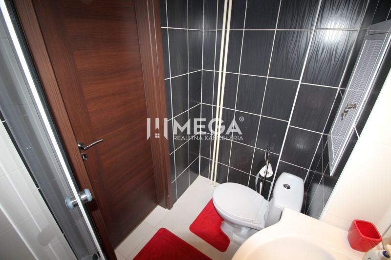 Fürdőszoba a nyaraló apartmanban zuhanyzóval, WC-vel és fekete csempékkel.