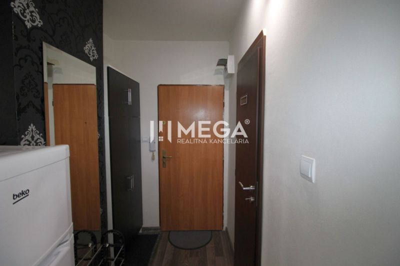 Nyaraló apartman folyosója fa dekor padlóval, tapétával és hűtőszekrénnyel.