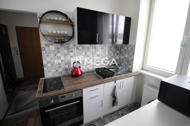A nyaraló apartman konyhája fekete szekrényekkel, főzőlappal és dekoratív burkolattal.