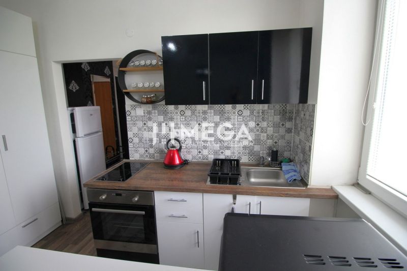 Konyha a nyaraló apartmanban fa dekor padlóval és geometrikus csempékkel a falon.