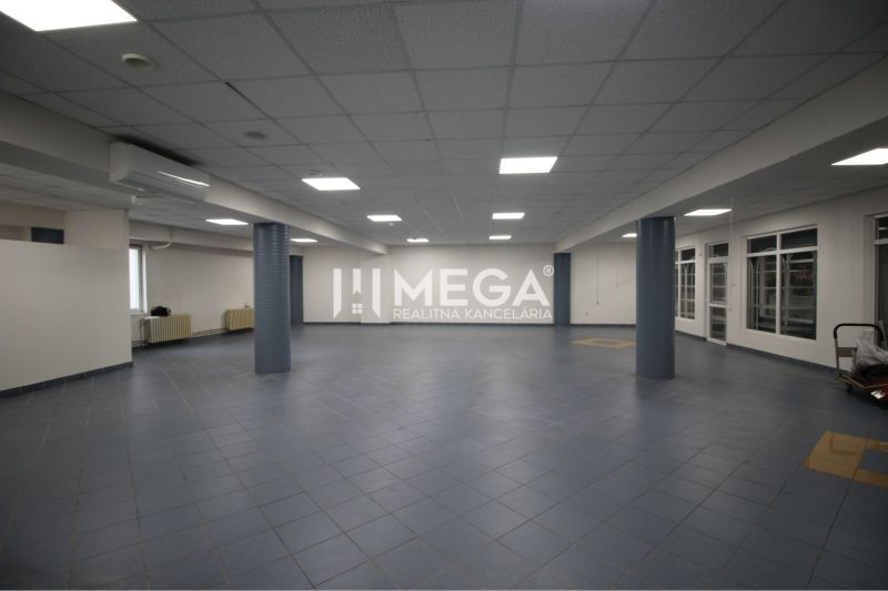 Tágas üzlethelyiségek sötét padlóburkolattal és álmennyezettel, alkalmas vállalkozásra.