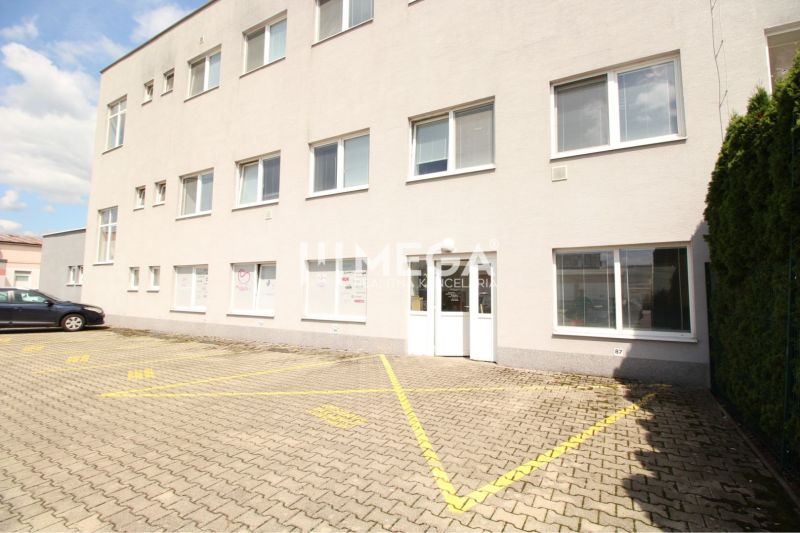 Kereskedelmi helyiségek a humennei Tolsztoj utcában parkolóhelyekkel és fehér homlokzattal.