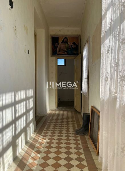 Folyosó egy családi házban színes csempével és függönnyel, a falon egy kép lóg.