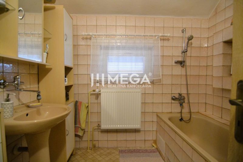 Fürdőszoba családi házban bézs csempével, káddal és mosdóval.