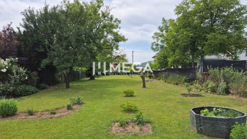 Családi ház kerthelyisége Lackócban gyepes területtel és fákkal.