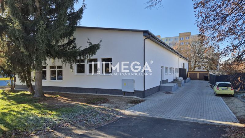 A Tyršova utcai üzlethelyiség épülete Humennéban fákkal körülvéve.