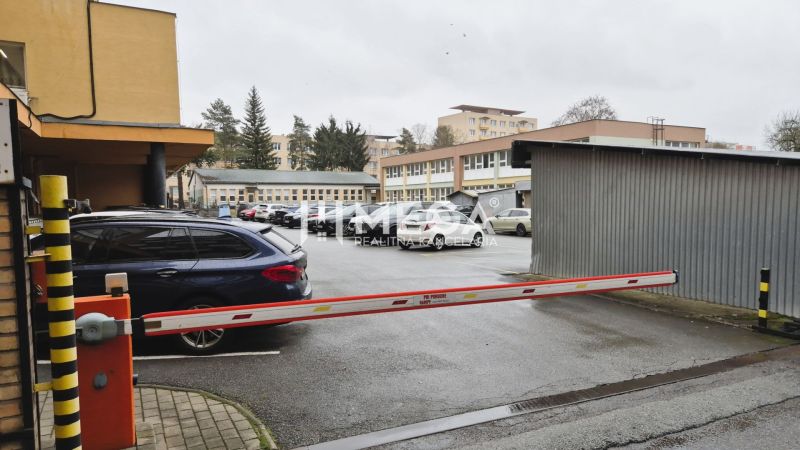 Irodák előtti parkoló a november 26. utcában, Humennéban, sorompóval és autókkal.