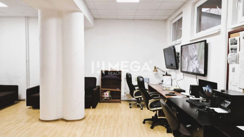 Iroda fa dekorációjú padlóval, asztalokkal, székekkel és képernyőkkel a falon.