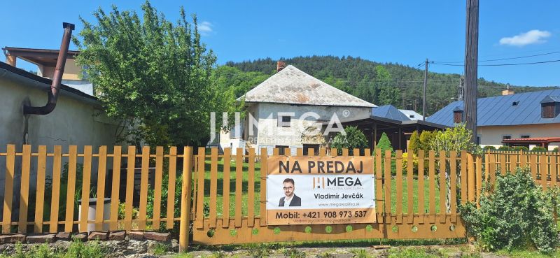 Családi ház eladó Kochanovce községben, zöld növényzettel körülvett kerítés mögött található.
