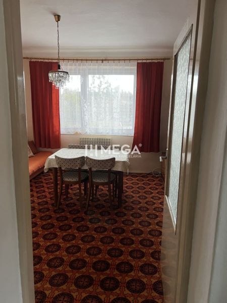 Családi ház belső tere piros dekorációjú szőnyeggel, étkezőasztallal és csillárral.