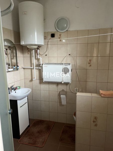 Fürdőszoba gázkazánnal és mosdóval családi házban, csempe, egyszerű berendezés.
