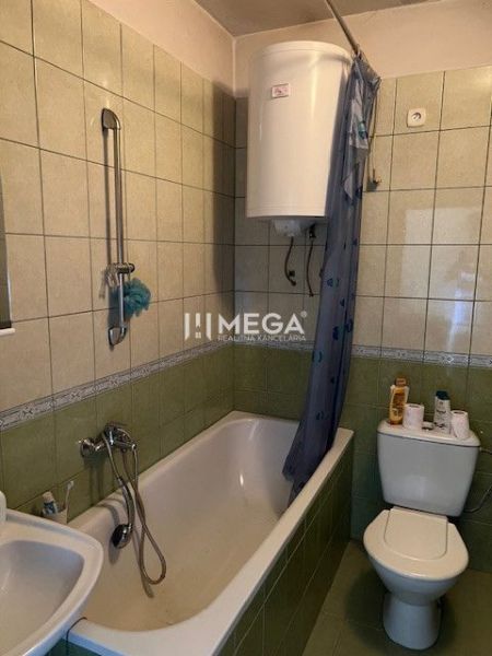 Fürdőszoba káddal és WC-vel, zöld csempével burkolva egy családi házban.