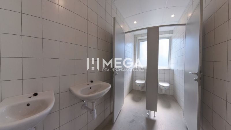 Mosdókagylóval és WC-vel ellátott szociális helyiség az irodákban, csempék a falakon.
