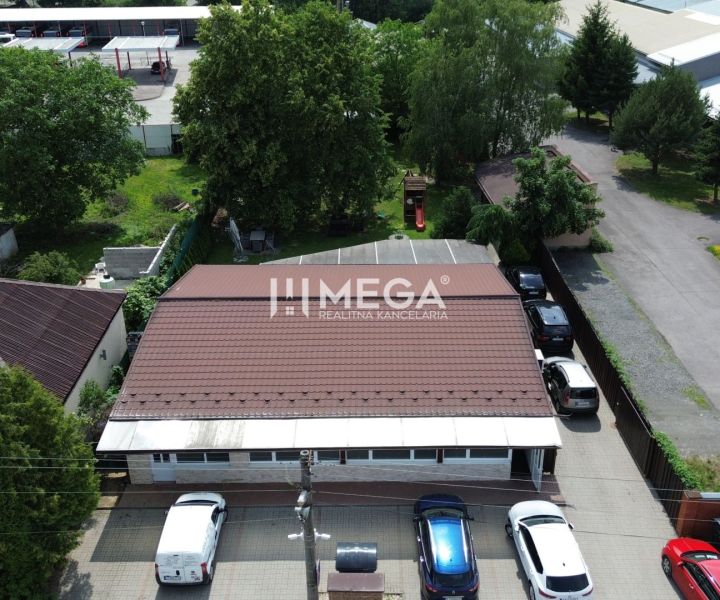 Vendéglátóhelyiségek a Budovateľská utcában, Vranov nad Topľou városában, autókkal és zölddel körülvéve.