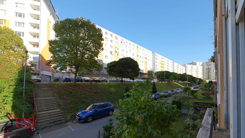 Rozkvet lakótelep Považská Bystricában lakóházakkal és parkoló autókkal.