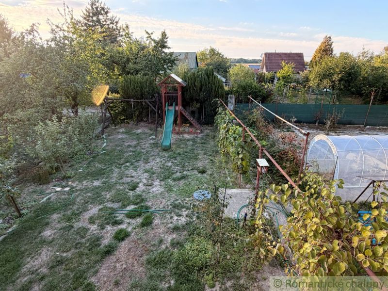 Kert gyepes területtel és csúszdával a házikó mellett Érsekújváron.