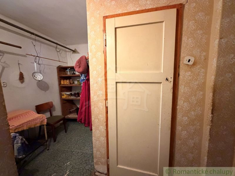Családi ház belső tere előszobával, székkel és polcokkal. Konyhai eszközök lógnak itt.