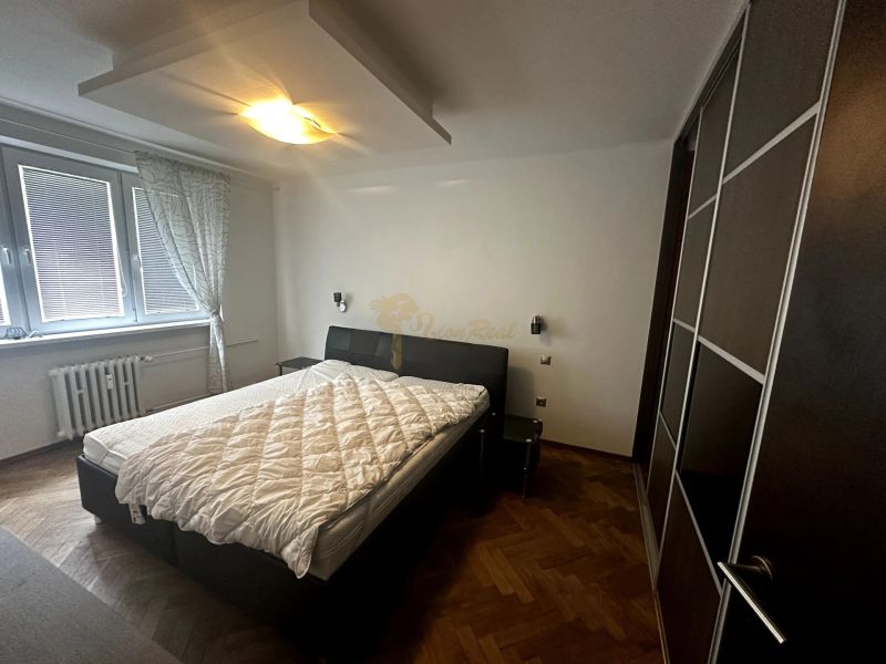 Hálószoba egy kétszobás lakásban, ággyal, gardróbszekrénnyel és fa dekoros padlóval.