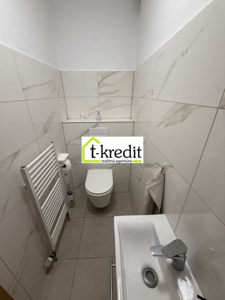 Családi ház fürdőszobája fehér csempékkel és mosdóval.