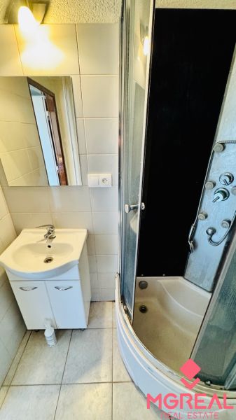 Fürdőszoba mosdóval és zuhanyzóval egy egyszobás lakásban.