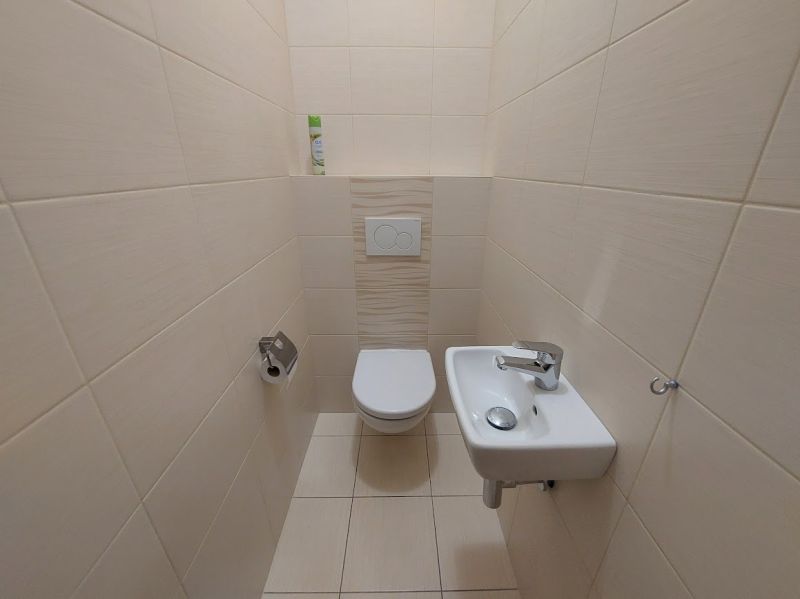 WC mosdóval egy háromszobás lakás belsejében, csempézett falak.
