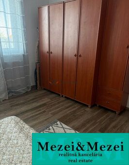 Szoba egy kétszobás lakásban szekrényekkel és fa dekorációjú padlóval.