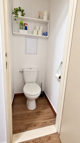 WC polccal és fa dekorációjú padlóval egy háromszobás lakásban.