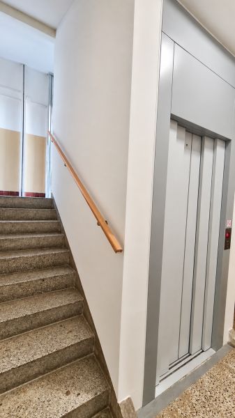 Lépcsőház korláttal és lifttel az épületben egy háromszobás lakás mellett.