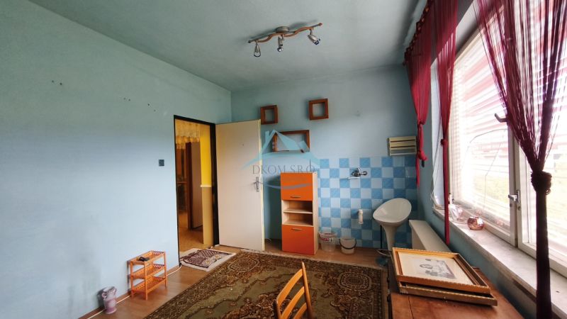 Szoba egy családi házban csempékkel, fa dekoros padlóval és nagy ablakkal.