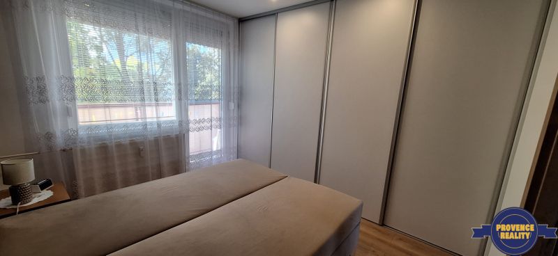 Hálószoba egy háromszobás lakásban nagy gardróbszekrénnyel és függönyös ablakkal.