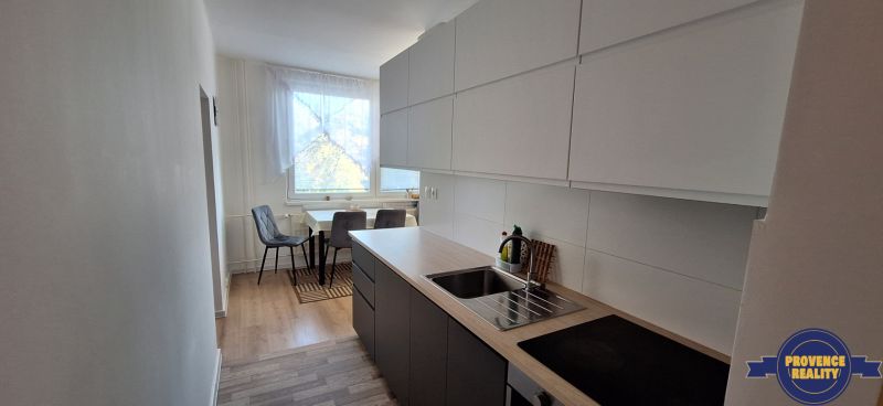 Konyha egy háromszobás lakásban, fa dekor padlóval és étkező sarokkal.