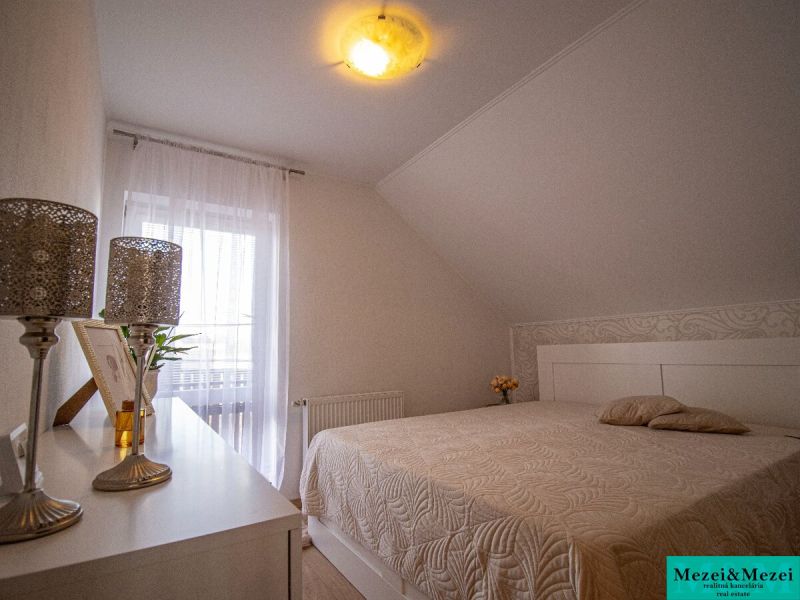 Hálószoba családi házban dekorációkkal, ággyal és lágy világítással.