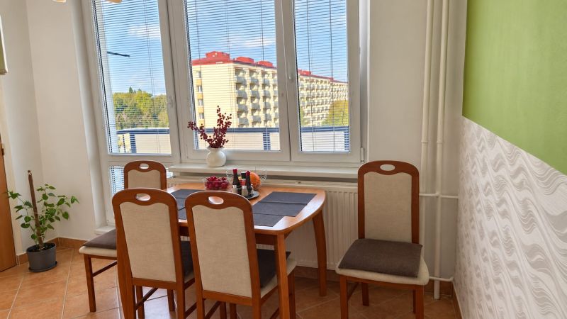 Étkező sarok fa székekkel és ablakkal egy háromszobás lakásban.