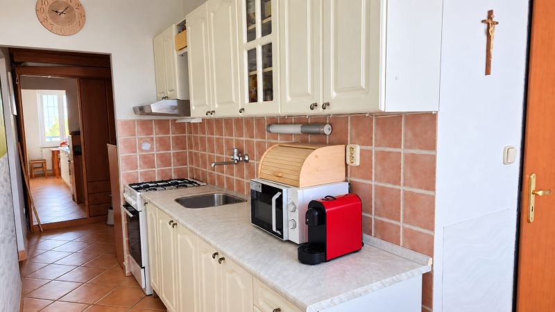 Konyha fehér szekrényekkel és kerámia burkolattal egy háromszobás lakásban.
