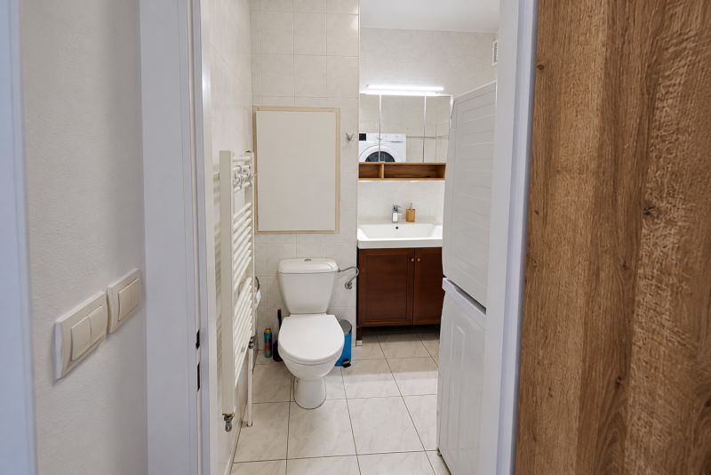 Fürdőszoba mosdóval, WC-vel és mosógéppel egy kétszobás lakásban.