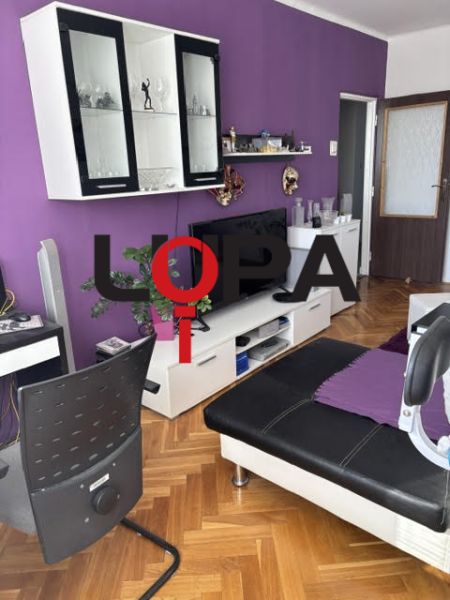 Nappali egy kétszobás lakásban kanapéval és bútorokkal, fa dekoros padlóval.