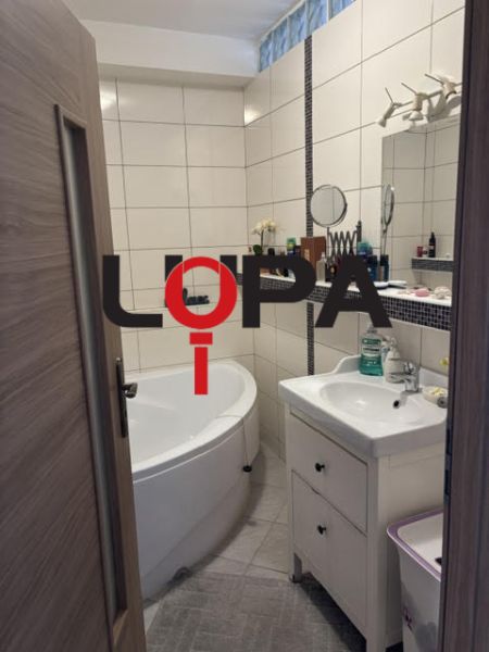 Fürdőszoba egy kétszobás lakásban káddal, mosdóval és fehér csempékkel.