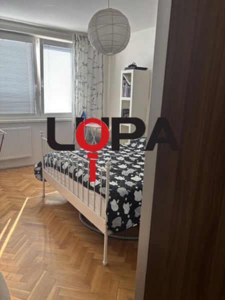 Hálószoba egy kétszobás lakásban, ággyal és fa dekorációjú padlóval.