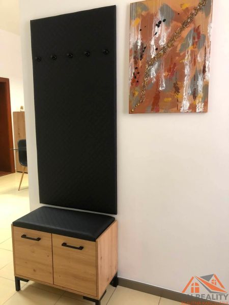 Komód és fogas fekete panellel a kétszobás lakás előszobájában.
