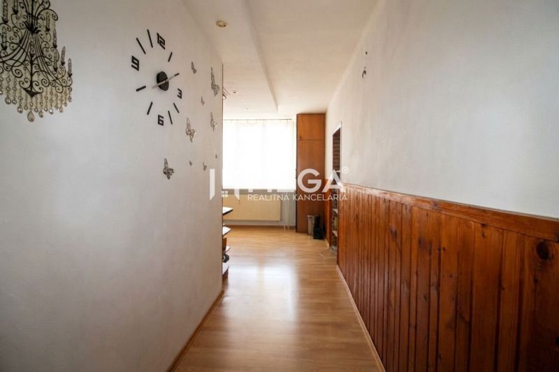 Egy háromszobás lakás folyosója fa mintázatú padlóval és fali órával.