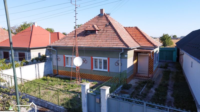 Családi ház Királyréven piros ferde tetővel és rendezett kerttel.
