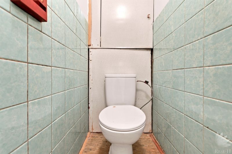 WC zöld csempével a kétszobás lakásban és fa mintázatú padlóval.