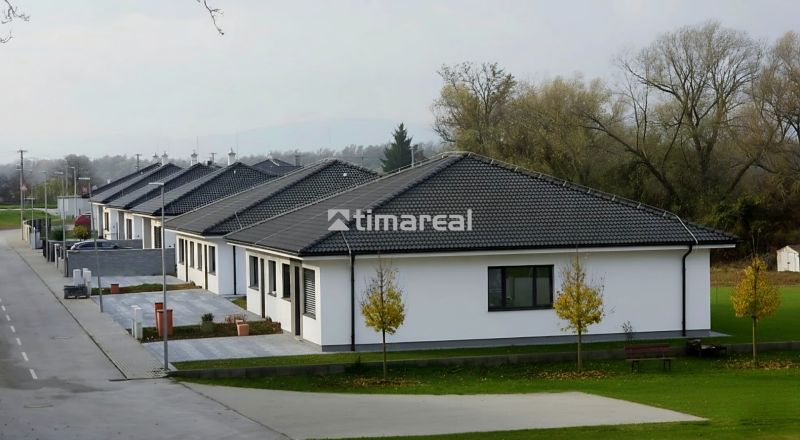 Sötét tetős családi házak Hôrka nad Váhom településen, zöldövezettel és úttal körülvéve.