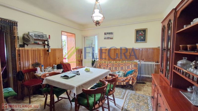 Nappali egy családi házban étkezőasztallal és vitrinnel.