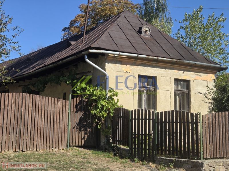Régi családi ház Hejcén ferde tetővel és fa kerítéssel.